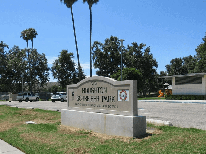 Houghton Schreiber Park sign with grass and the road in the background